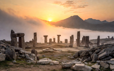 Göbekli Tepe at sunrise: ancient T-shaped pillars emerging from mist on a limestone ridge in Turkey, with dramatic golden light and mountains in the background.