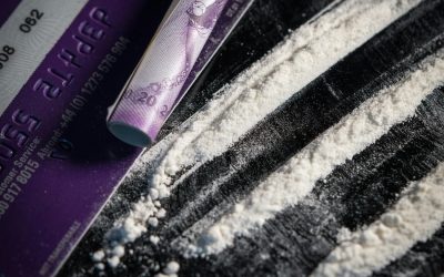 Close-up of illicit substances arranged on a flat surface, alongside a credit card and a makeshift straw.