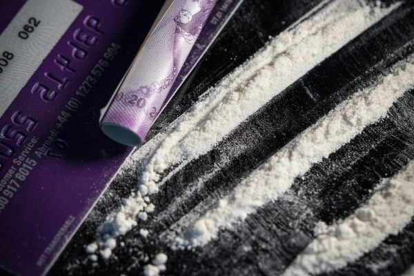 Close-up of illicit substances arranged on a flat surface, alongside a credit card and a makeshift straw.