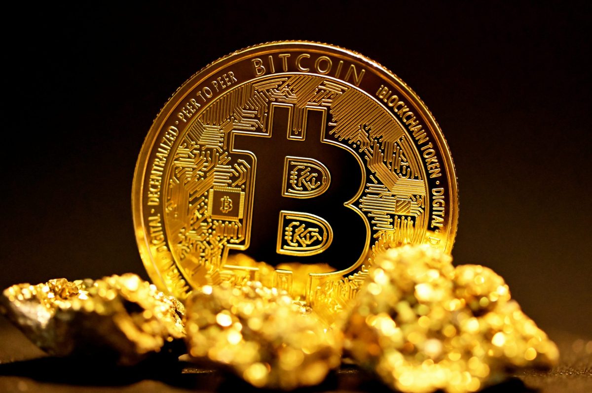 Close-up of a physical Bitcoin coin surrounded by gold nuggets, symbolizing cryptocurrency and traditional stores of value.
