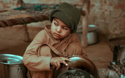Image of a child living in poverty, cleaning dishes in the streets.