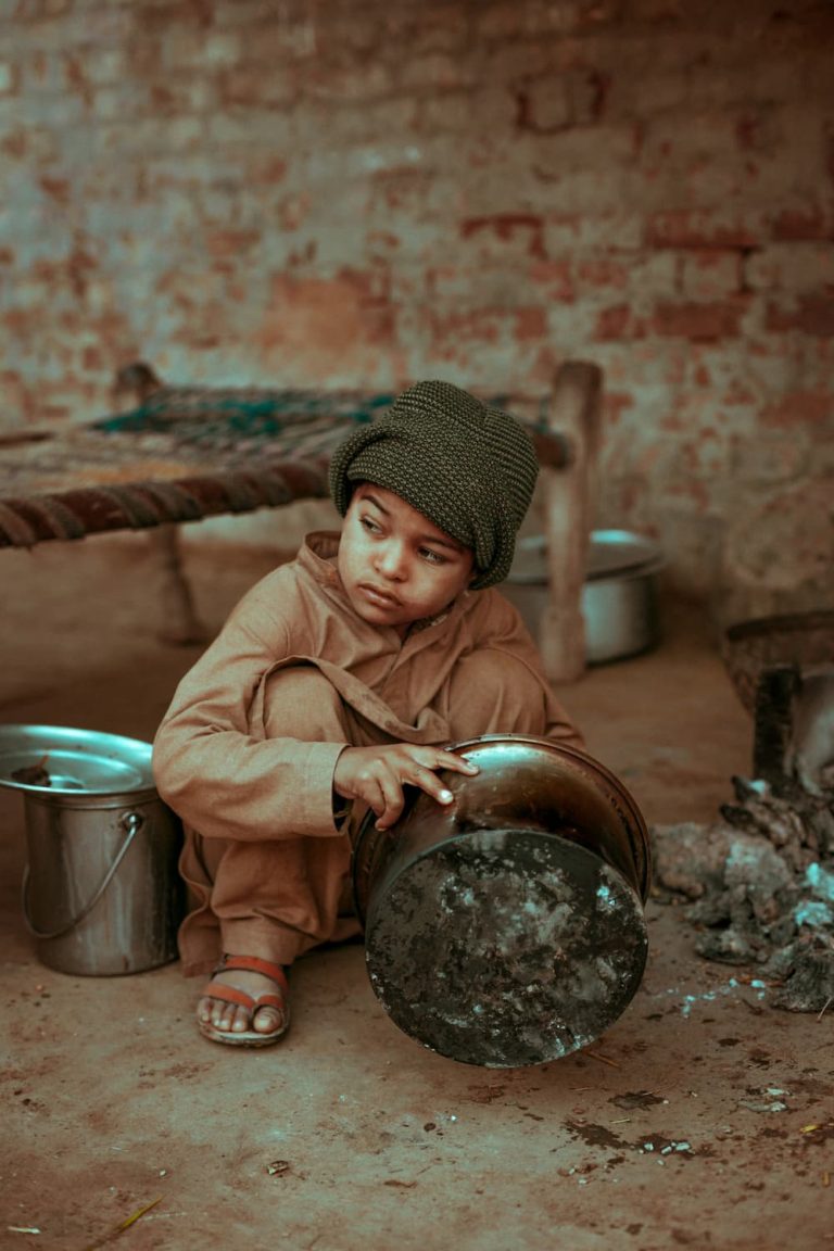 Image of a child living in poverty, cleaning dishes in the streets.