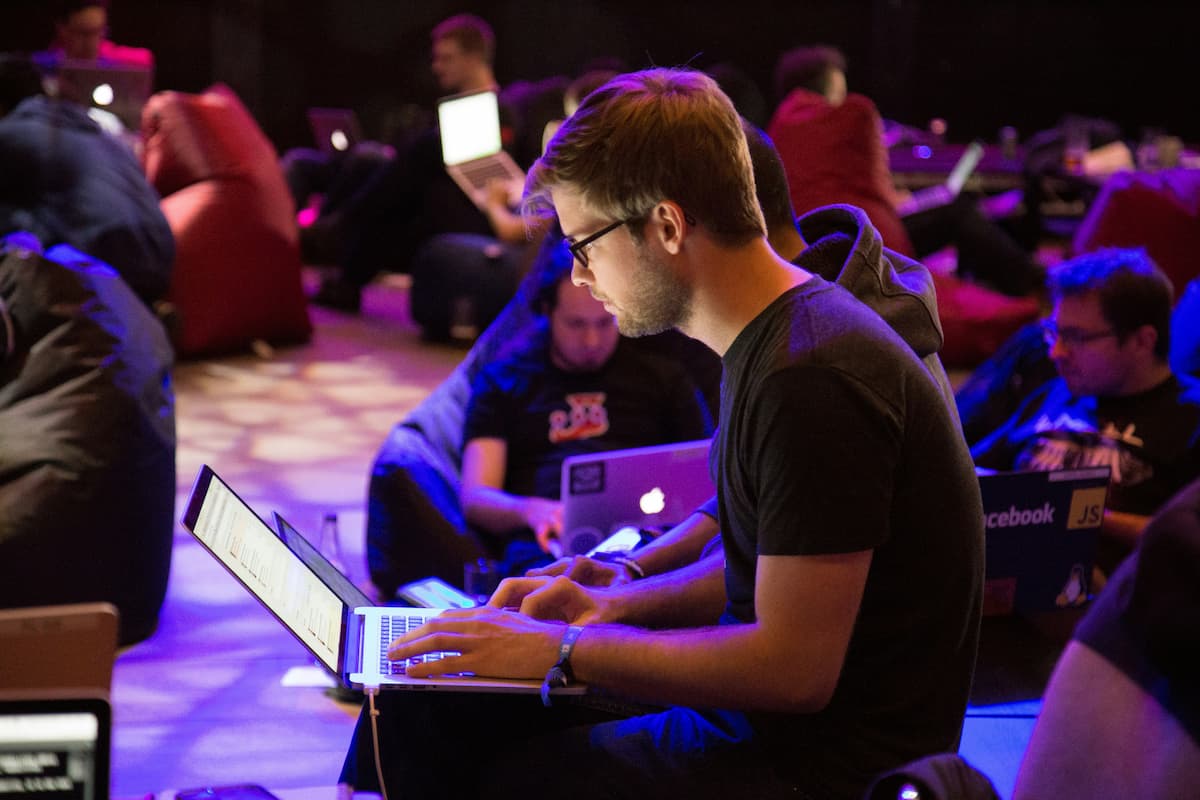 Image of a man with glasses working on his computer, surrounded by many others doing the same.