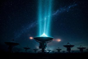 Large radio telescope array at night receiving a dramatic glowing cyan technosignature signal from deep space under the Milky Way, symbolizing potential discovery of intelligent alien life.