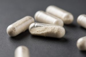 Close-up of transparent antibiotic capsules filled with white powder on a dark surface.