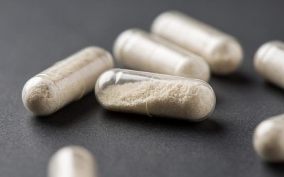 Close-up of transparent antibiotic capsules filled with white powder on a dark surface.