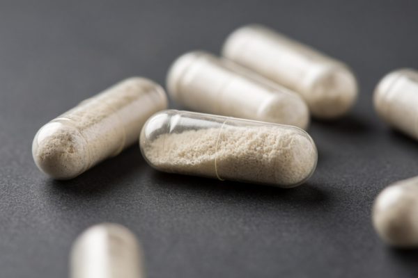 Close-up of transparent antibiotic capsules filled with white powder on a dark surface.