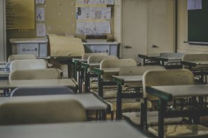 Empty classroom with rows of student desks and chairs.