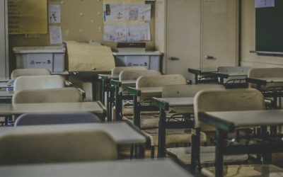 Empty classroom with rows of student desks and chairs.