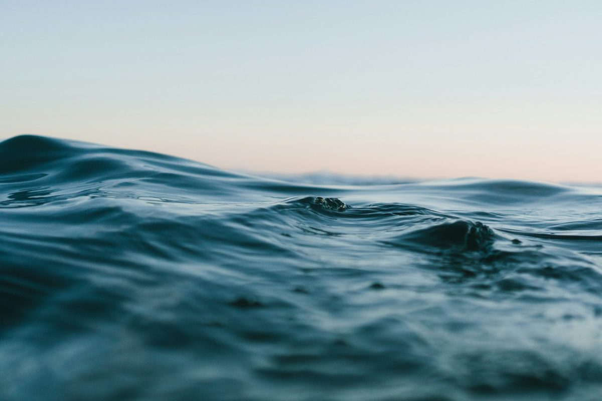 Close-up of gentle ocean waves under a soft sky, representing the movement of water in the natural water cycle.